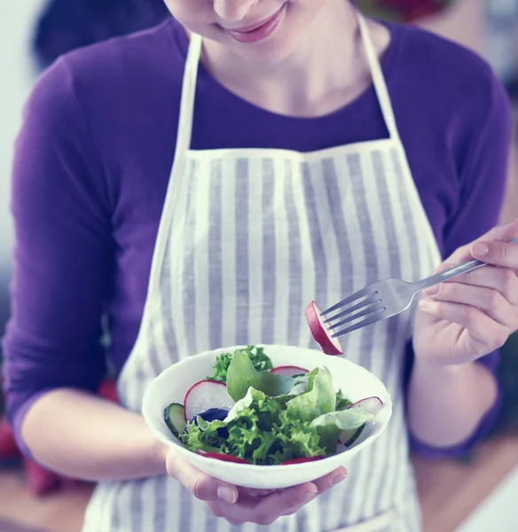 Jonge vrouw die verse salade eet in de moderne keuken — Stockfoto