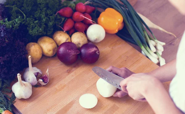 Mutfakta sebze doğrayan genç bir kadın.