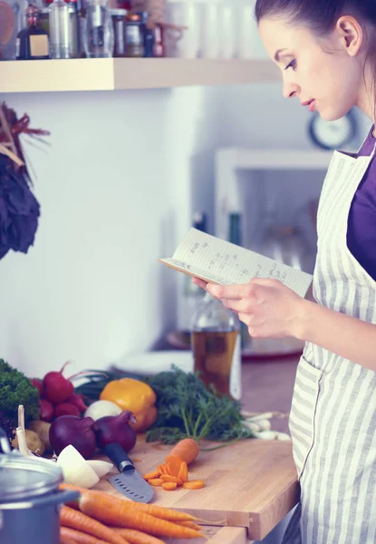 Junge Frau liest Kochbuch in der Küche und sucht Rezept — Stockfoto