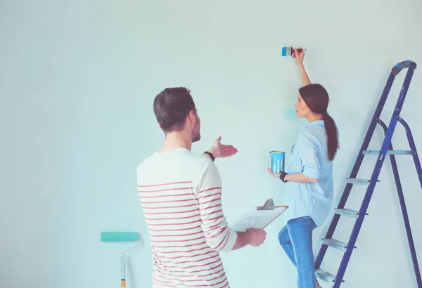 Portret van een vrolijk glimlachend jong stel dat de binnenmuur van een nieuw huis schildert. jong stel — Stockfoto