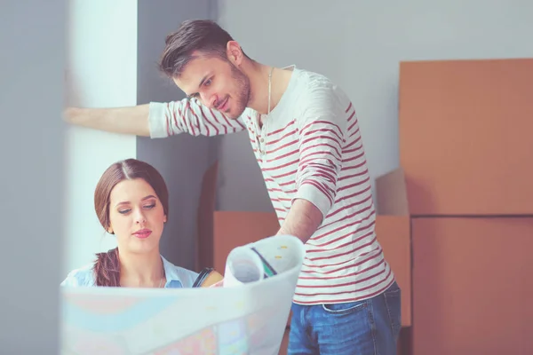 Young couple sitting on the floor and looking at the blueprint of new home. Young couple — Stock Photo, Image