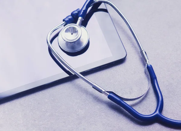 Medicinsk utrustning: blå stetoskop och surfplatta på grå bakgrund. — Stockfoto