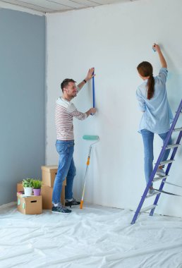 Yeni evin içini boyayan mutlu, genç bir çiftin portresi. Genç çift