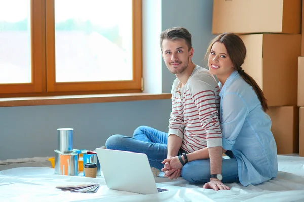 Unga paret sitter på golvet i sin nya lägenhet. Ungt par — Stockfoto