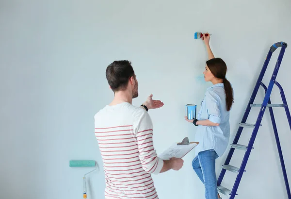 Portret van een vrolijk glimlachend jong stel dat de binnenmuur van een nieuw huis schildert. jong stel — Stockfoto