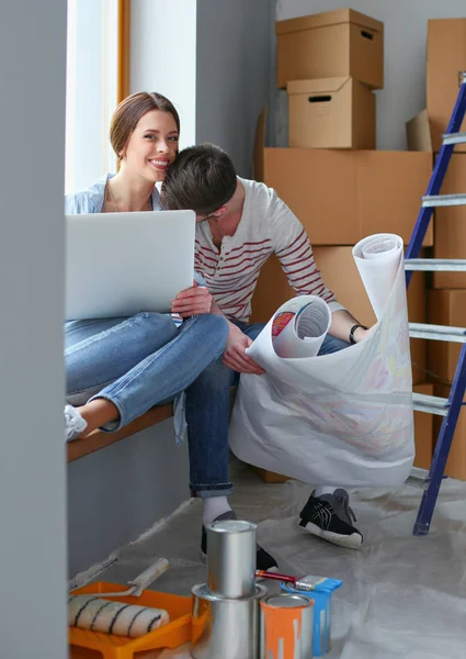 Casal jovem sentado no chão e olhando para a planta da nova casa. Casal jovem — Fotografia de Stock