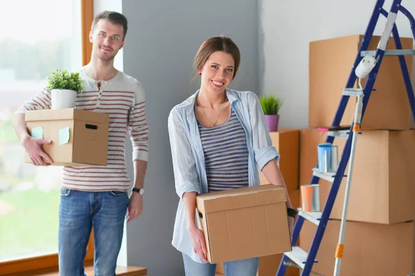 Glada unga par uppackning eller packa lådor och flytta till ett nytt hem. Glada unga par — Stockfoto