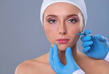 Güzel kadın yüz kozmetik enjeksiyon. Gri arka plan üzerinde izole. Kozmetik enjeksiyon