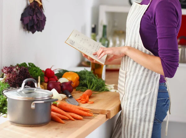 Jonge vrouw lezen kookboek in de keuken, op zoek naar recept. Jonge vrouw — Stockfoto