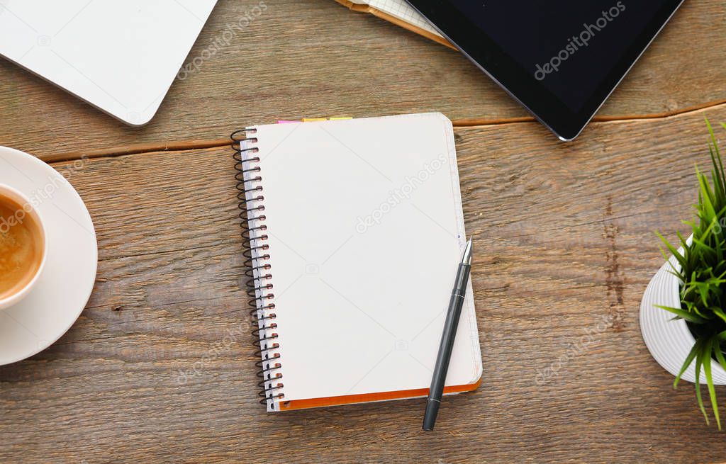 Top view image of open notebook with blank pages next to cup of coffee on wooden table.