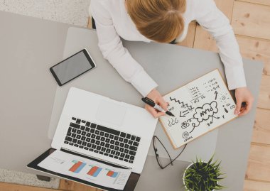 Masada dizüstü bilgisayarla oturan iş kadınının portresi.