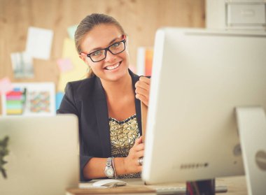 Moda tasarımcıları stüdyoda çalışıyor. Masanın üzerinde oturuyorlar.