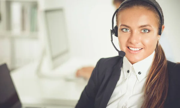 Glückliche Frau trägt Headset und sitzt auf dem Schreibtisch — Stockfoto