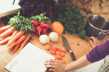 Mutfakta sebze doğrayan genç bir kadın.