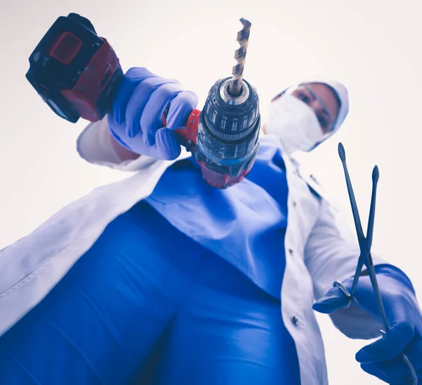Visa underifrån av maskerad läkare skrämma patienten med en borr . — Stockfoto