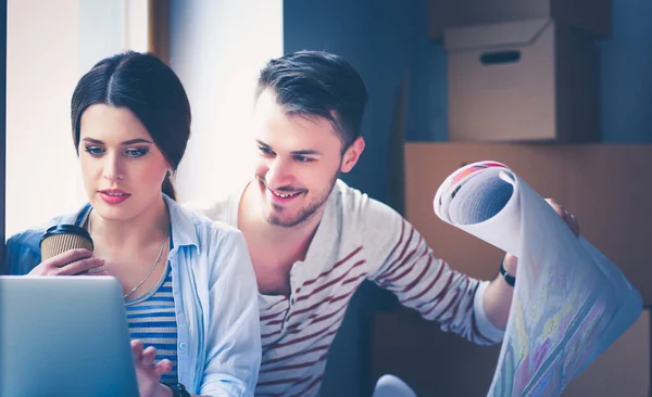 Jong stel zit op de vloer en kijkt naar de blauwdruk van een nieuw huis — Stockfoto