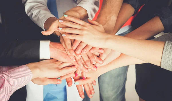 Çeşitli meslekleri olan insanların portresi ellerini birbirinin üstüne koyuyor.