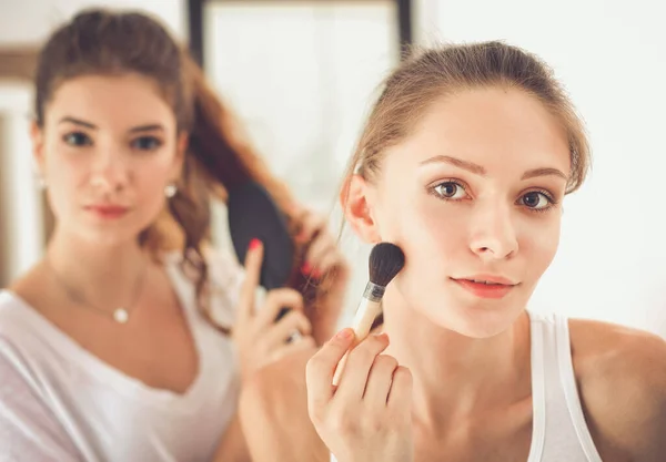 Krásné dívky při pohledu do zrcadla a použití kosmetiky s velkým štětcem — Stock fotografie