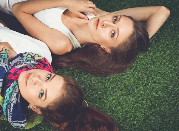 Dvě krásné dívky ležící na čerstvé zelené trávě — Stock fotografie
