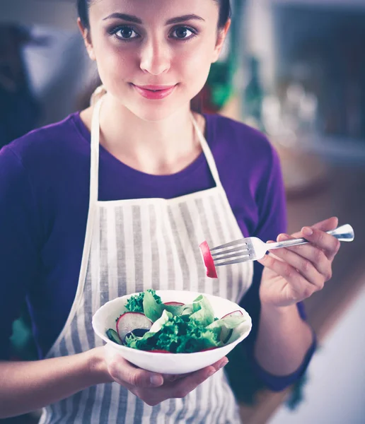 Een jonge vrouw die salade eet in haar keuken . — Stockfoto