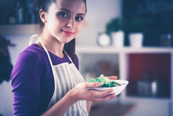 Una joven mujer comiendo ensalada en su cocina . — Foto de Stock