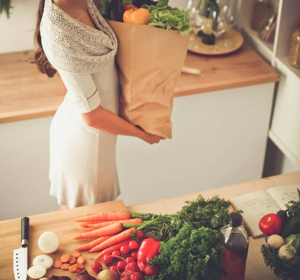 Junge Frau hält Einkaufstüte mit Gemüse in der Küche — Stockfoto
