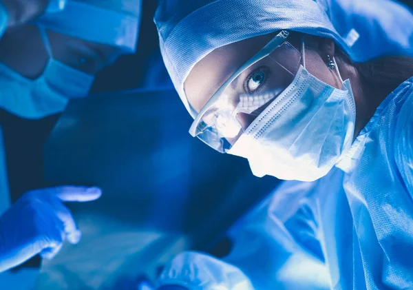 Chirurgen die aan een patiënt werken in een operatiekamer.. Stockfoto