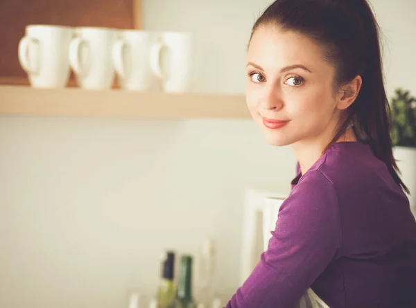 Jeune femme debout dans sa cuisine près du bureau Photo De Stock