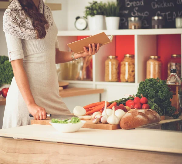 Jonge vrouw die groenten snijdt in de keuken Stockfoto