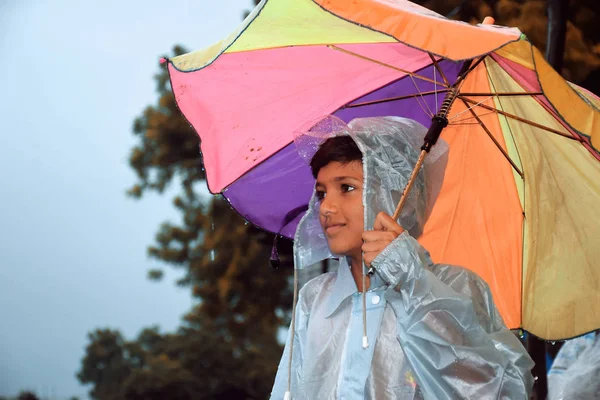 Ein indischer Junge, der wegsieht und Regenbogen im nassen Wasser trägt — Stockfoto