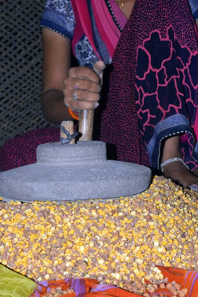 A village woman's hand, grinds gram in an old hand operated flour mill.
