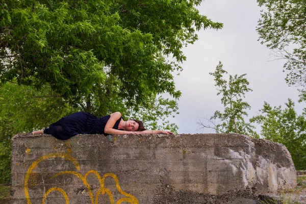 Bir taş parapetin üzerinde yalan siyah elbiseli kız