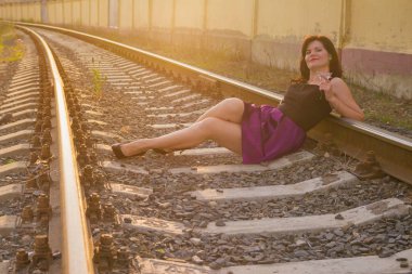 Demiryolu pistinde bir elbiseyle bir genç kadın