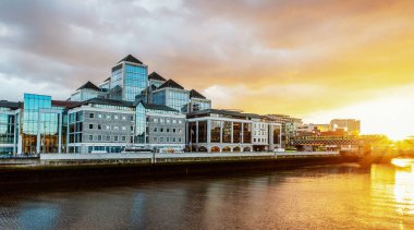 Liffey Nehri sahilindeki modern binalar. Dublin'de gün batımı ve bulutlu gökyüzü.