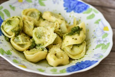 Ev yapımı vejetaryen İtalyan biyo-yumurtası taze tortelloni makarna zeytin yağı ve parmesan peyniri ile süslenmiş peynir için.