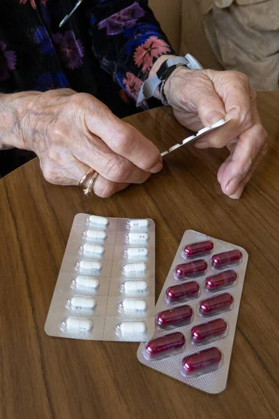 old woman preparing her pills with medical remote assistance button on the wrist