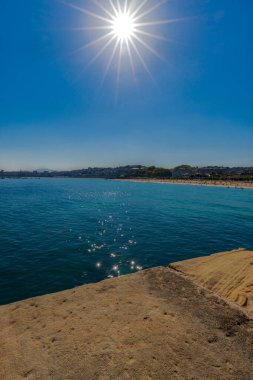 San Sebastian Ondarreta plajı, La Concha körfezi. Cantabrian Denizi, Bask Ülkesi, İspanya, Euskadi. Güneş bir yıldız oluşturuyor ve sudan yansıyor.