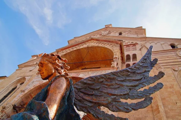 Blue Metal winged Angel Statue in front of the Santa Maria Matricolare Cathedral view from below and against the blue sky. Cathedral Duomo in Verona. Italy, Europe.