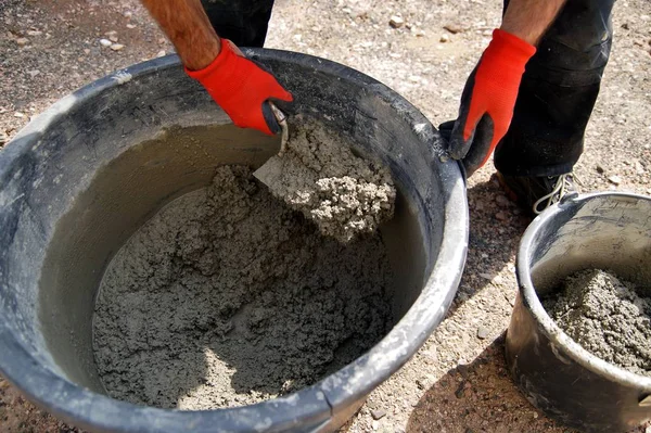 Foundation and form work. Male Worker hands shovels a wet mix of concrete in a bucket at a construction site.