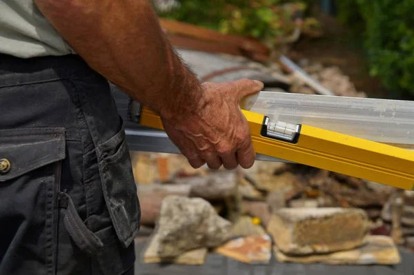 back view of worker holding a Spirit Level and a straightedge in hand.