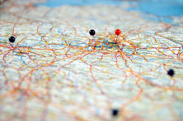 close up of pin sticks into a real map. travelling to berlin. pin marking location on map. maps navigation with red and black color point markers, design background. Travel concept with red and black push pins.