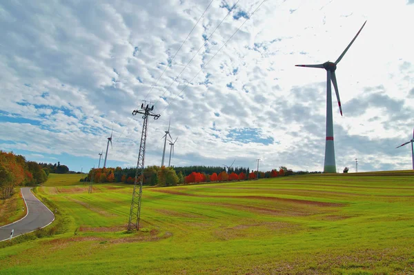 Wind turbines and High voltage tower against the sun, autumn landscape. high-tension pylons against cloudy sky. power line transmission tower in along the road. alternative energy, new natural scenery
