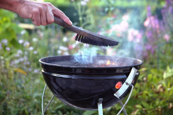 Cleaning a grill. Male hand cleans round grill with stiff brush. preparation of a grill before cooking. man is cleaning a grill at garden