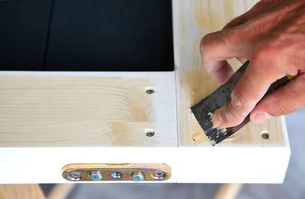 woodwork. Close-up Putty knife in man's hand. DIY worker applying filler to the wood. Removing holes from a wood surface. Preparation of wood before impregnation with varnish. Application of putty.