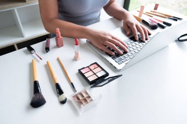 Güzellik blogger mevcut güzellik kozmetik ön tablet oturan. Güzel kadın kozmetik kullanımı inceleme online pazarlama için makyaj