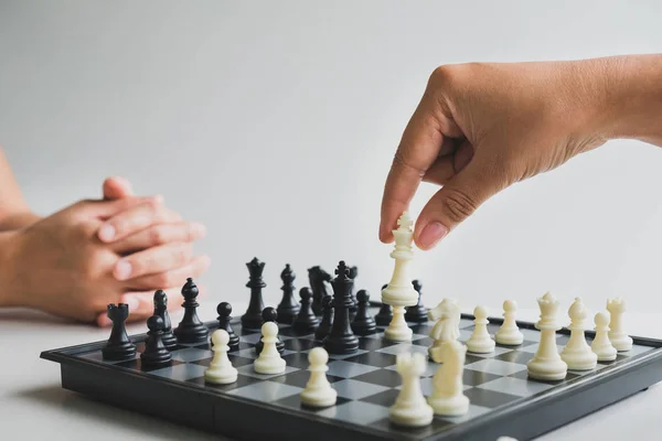 Рука тримає шахові фігури на борту з білим тлом, спрямованим на успіх бізнес-стратегії — стокове фото