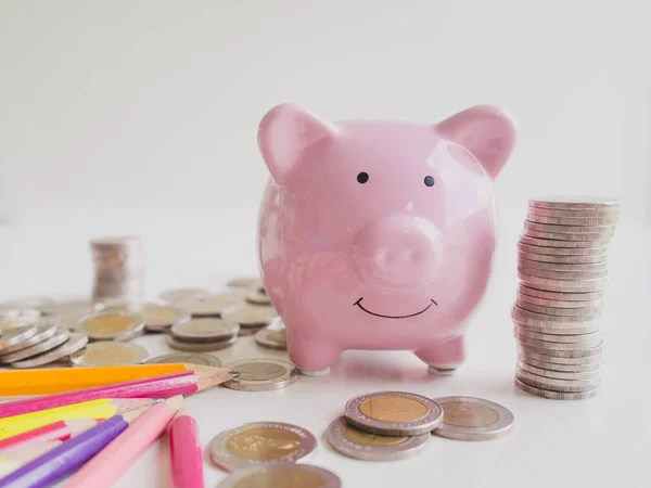 Pink Piggy bank, e lápis coloridos brilhantes com pilha de moedas, economizando dinheiro para o futuro plano e conceito de fundo de aposentadoria — Fotografia de Stock