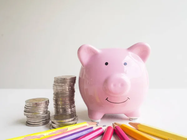 Piggy bank rosa com pilha de moedas e lápis coloridos brilhantes, economizando dinheiro para o futuro plano e conceito de fundo de aposentadoria — Fotografia de Stock