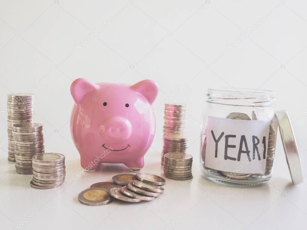 Pink Piggy bank with coins pile saving money in year one, Saving money for future plan and retirement fund concept