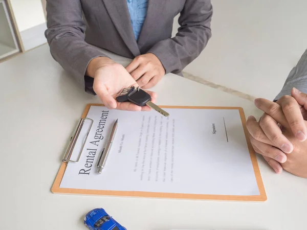 Car saleswoman giving the key to customer after signed a car rental service lease contract